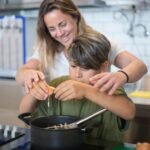 A mother and son enjoy bonding time while cooking together in a modern kitchen.