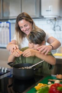 A mother and son enjoy bonding time while cooking together in a modern kitchen.